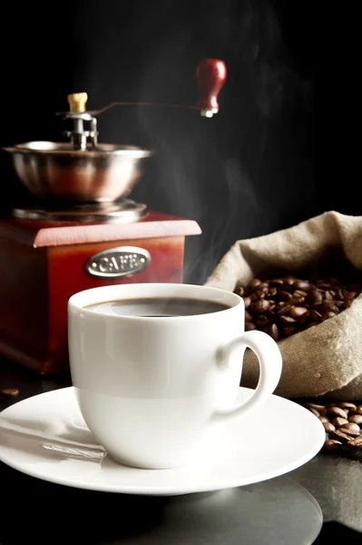 Cup of coffee with mill,bag full of coffee beans on black — Stock Photo, Image