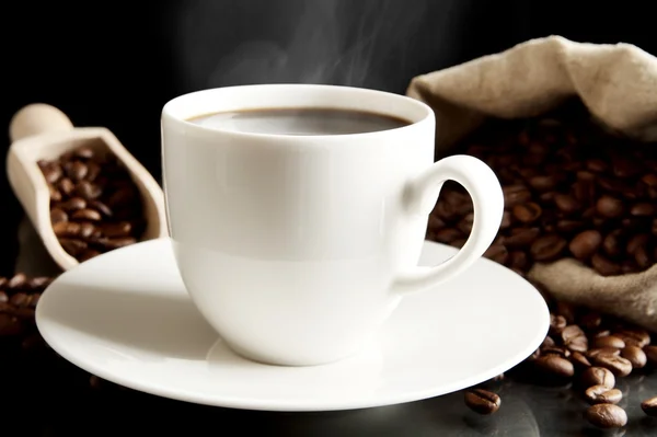 Tasse de café avec soucoupe avec sac avec grains de café sur noir — Photo