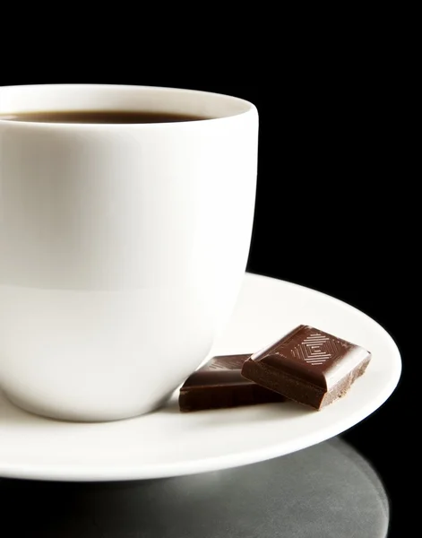 Tasse Kaffee mit Schokolade und Untertasse auf schwarz — Stockfoto