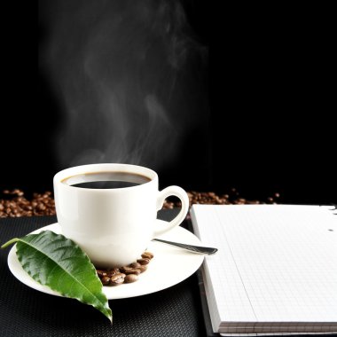Cup of coffee with haze with notebook and coffee leaf at breakfast clipart