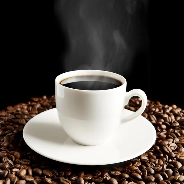 Чашка кофе с туманом и кофейными зёрнами на черном — стоковое фото