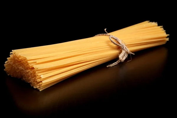 Long pasta raw isolated on black table — Stock Photo, Image