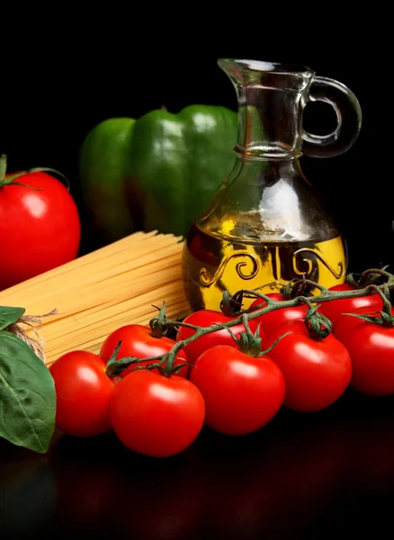 Длинная макароны сырой изолированы на черном с помидорами и оливковым маслом — стоковое фото