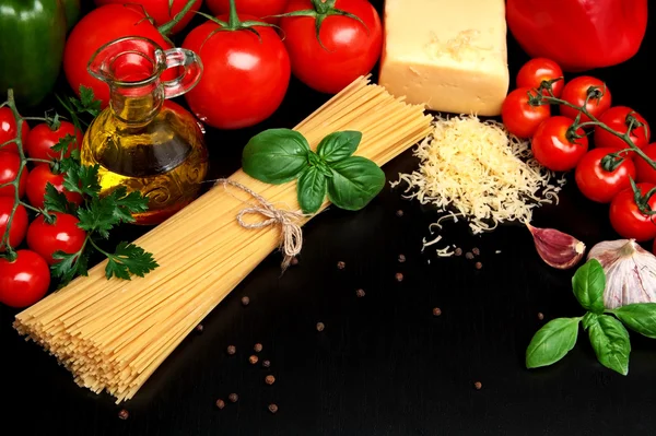 Těstoviny syrové izolovaných na černé s rajčaty, olivový olej, česnek — Stock fotografie