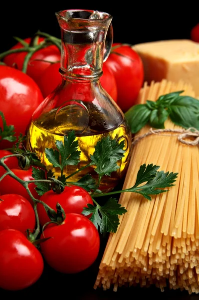 Nudeln roh isoliert auf schwarz mit Tomaten, Olivenöl, Knoblauch verti Stockfoto