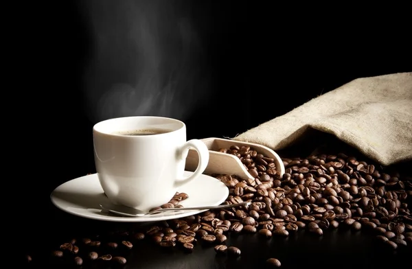 Xícara de café com saco com grãos de café na mesa preta — Fotografia de Stock