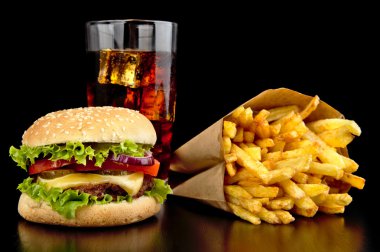 Menü - büyük çizburger patates kızartması ve kola siyah arka plan üzerine siyah ahşap masa üzerinde bardak