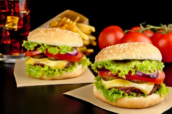 Cheeseburgare, pommes frites på trä skrivbord på svart — Stockfoto