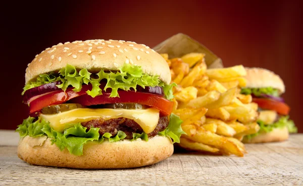 Grand cheeseburger simple avec verre de cola sur un bureau en bois sur fond rouge — Photo