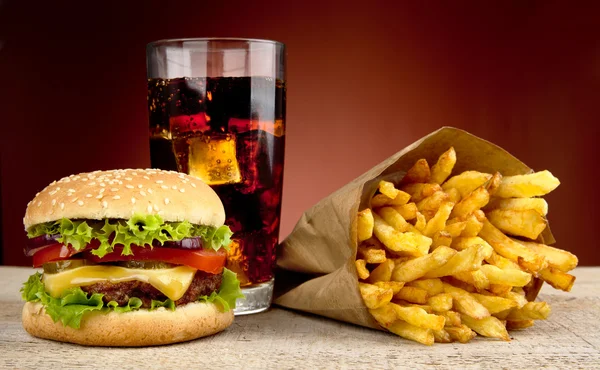 Ostburgare med glas cola och pommes frites på röda spotlight bakgrund — Stockfoto