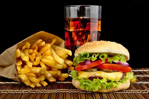 Ostburgare med pommes frites med glas cola på trä matta på svart — Stockfoto