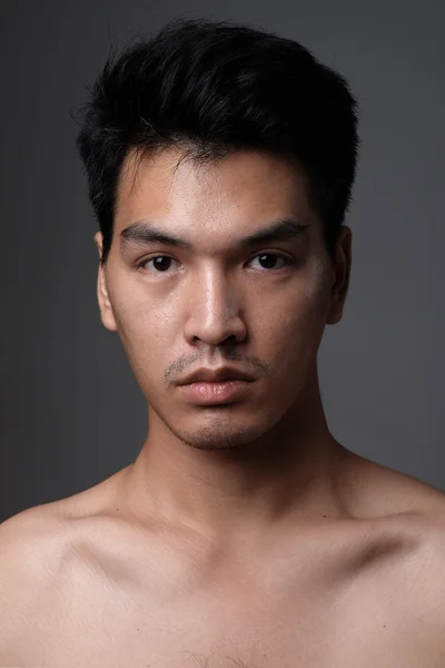 Asiatiska man stående med sminkningen Visa hans verkliga hud i grå bakgrund - mjukt fokus — Stockfoto