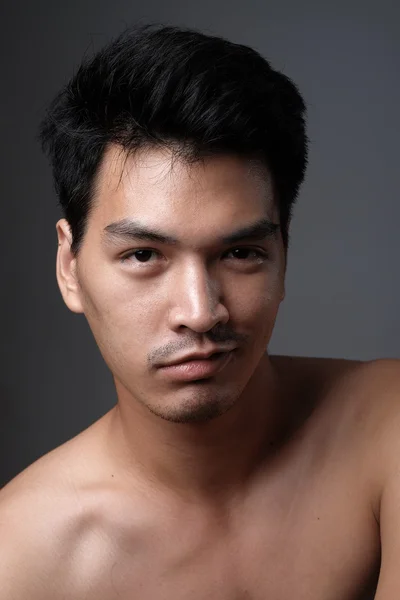 Retrato de hombre asiático sin maquillaje muestra su piel real en fondo gris - enfoque suave — Foto de Stock