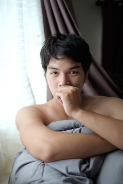 Gömleksiz Asya adamı uyandır yatakta battaniye - yumuşak odak ile