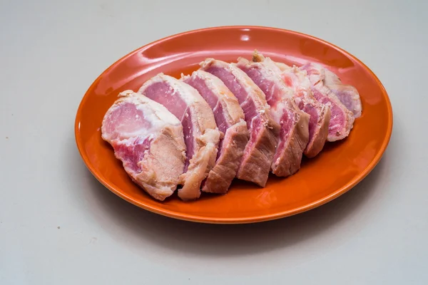 Cerdo crudo en rodajas en el plato de naranja - Ingrediente —  Fotos de Stock