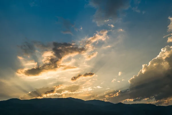 Zonsondergang achter berg met prachtige sunbeam via de wolk — Stockfoto