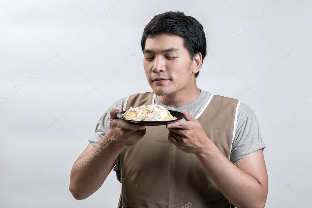 Asian man in apron with spaghetti carbonara