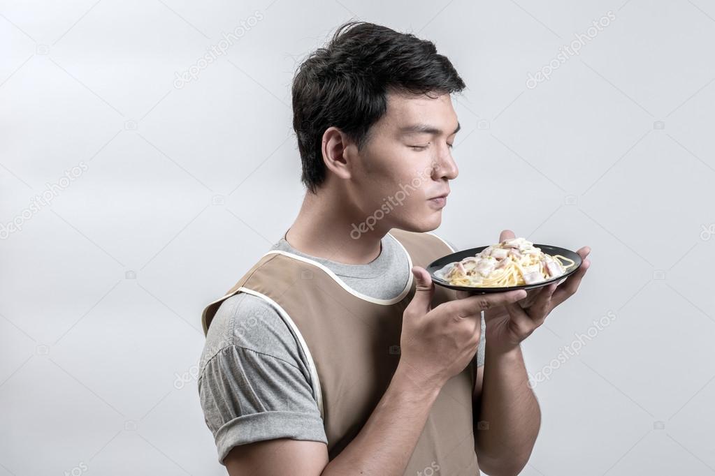 Asian man in apron with spaghetti carbonara