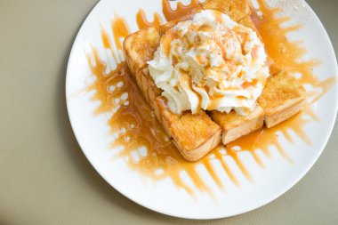 Golden honey toast in the white dish with whipped cream on top