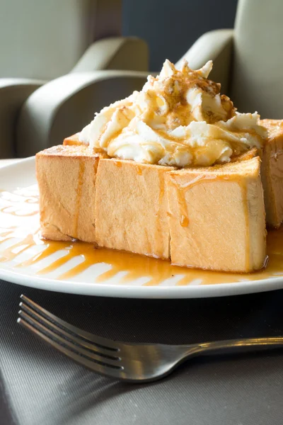 Torrada de mel dourado no prato branco com chantilly em cima — Fotografia de Stock
