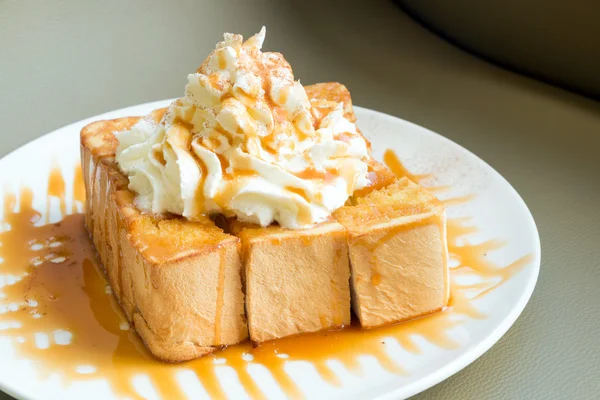 Golden honey toast in the white dish with whipped cream on top — Stock Photo, Image