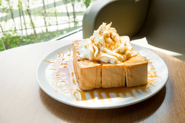 Toast au miel doré dans le plat blanc avec crème fouettée sur le dessus — Photo