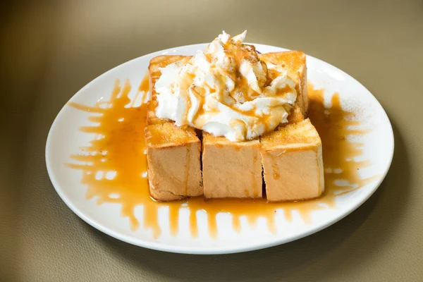 Goldener Honigtoast in der weißen Schüssel mit Schlagsahne darüber — Stockfoto