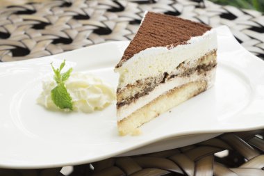 Tiramisu pasta beyaz tabak içinde krem şanti ile servis
