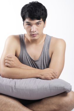 Asya adam oturmuş ve yastık tutan gri pijama