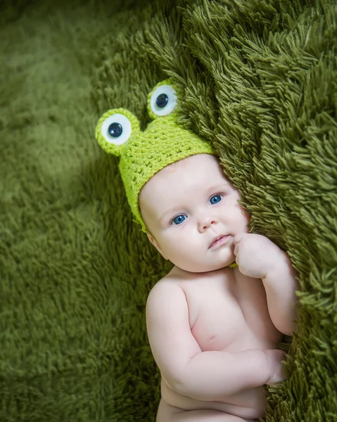 Новорожденный ребенок в шляпе лягушки лежал на животе — стоковое фото