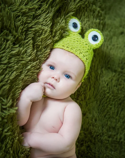 Bebê recém-nascido em um sapo chapéu deitado no estômago — Fotografia de Stock