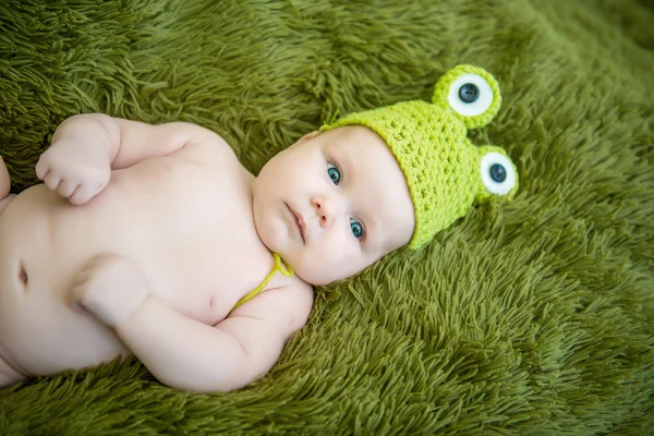 Bebê recém-nascido em um sapo chapéu deitado no estômago — Fotografia de Stock