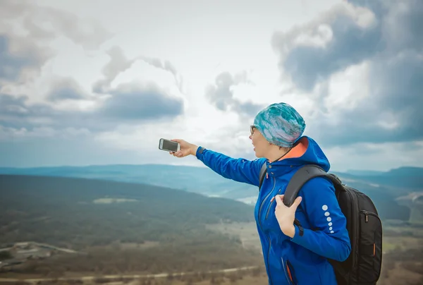 Girl tourist on background of the mountains with a mobile phone — Stock Photo, Image