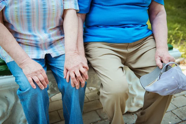 Close-up van handen van oudere mannen en vrouwen. Senior paar zittend op een bankje met wandelstok. — Stockfoto