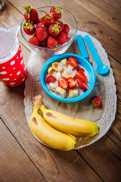 Batido de fresa y plátano en un vaso sobre una mesa de madera azul . —  Fotos de Stock