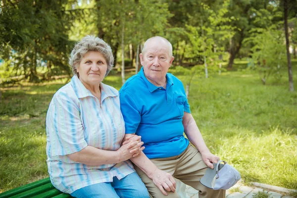 Pareja mayor sentada en un banco del parque con bastón. Pareja mayor relajándose al aire libre en un día de verano . Imagen de stock