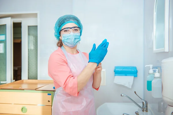 Жіночий хірург одягає рукавички перед операцією — стокове фото
