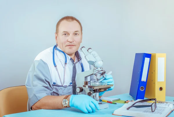 Retrato de um médico masculino com um microscópio em laboratório — Fotografia de Stock
