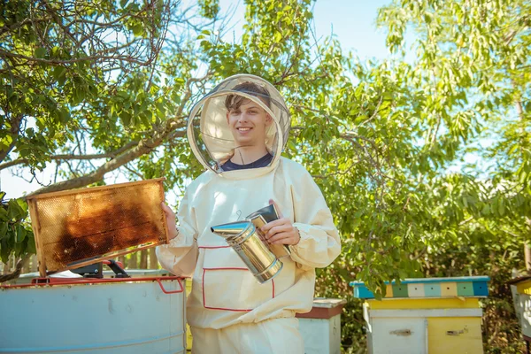 L'apiculteur tient à la main un cadre avec des rayons de miel et des abeilles — Photo