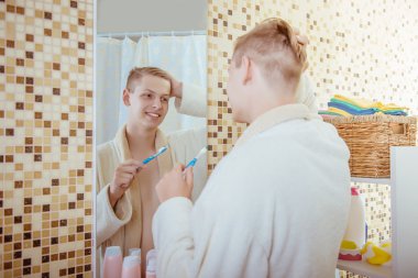 genç adam banyoda Dişlerini fırçalıyor화장실에서 그의 솔 질 하는 젊은이