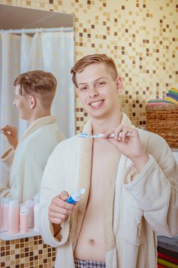 genç adam banyoda Dişlerini fırçalıyor화장실에서 그의 솔 질 하는 젊은이