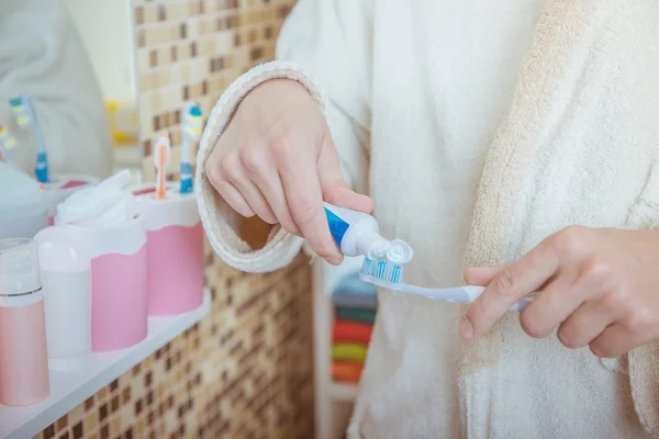 Фото крупным планом человека, надевающего зубную пасту на зубную щетку в ванной комнате — стоковое фото