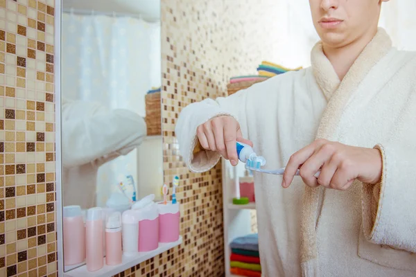 Foto de close-up do homem colocando pasta de dentes na escova de dentes no banheiro — Fotografia de Stock