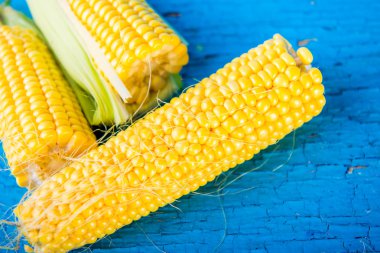 Tahta bir masada çiğ mısır.