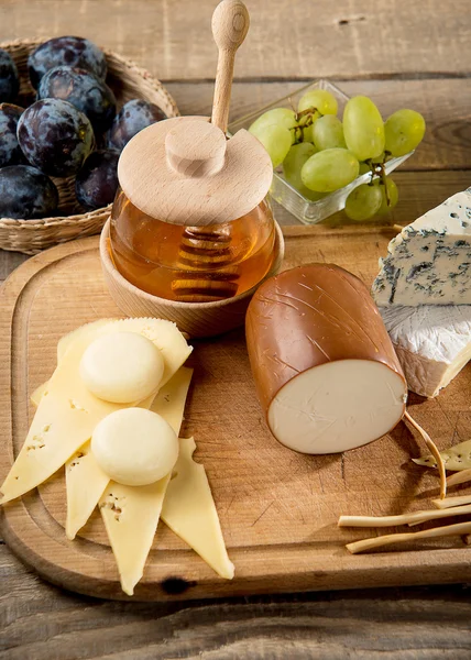 Various types of cheese, grapes, honey,  bottle of wine — Stock Photo, Image
