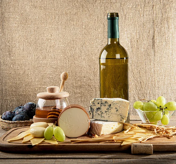 Various types of cheese, grapes, honey,  bottle of wine — Stock Photo, Image