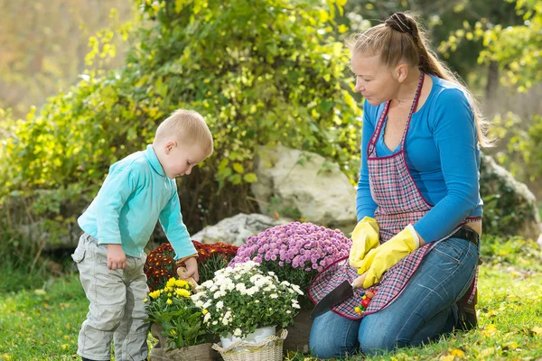 Young woman with a child are planting flowers — Stok fotoğraf