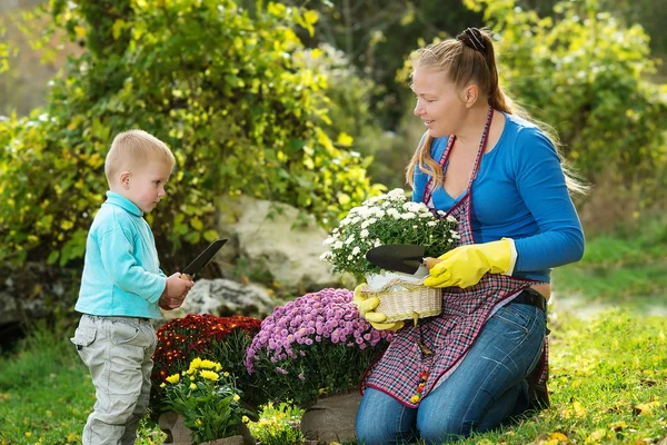 Young woman with a child are planting flowers — 스톡 사진