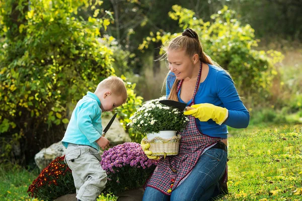 Young woman with a child are planting flowers — Zdjęcie stockowe