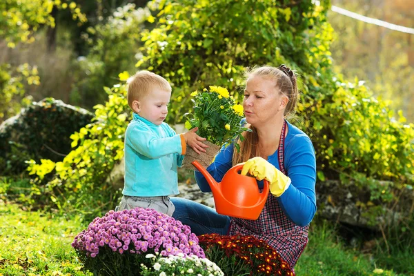 Young woman with a child are planting flowers — Stok fotoğraf